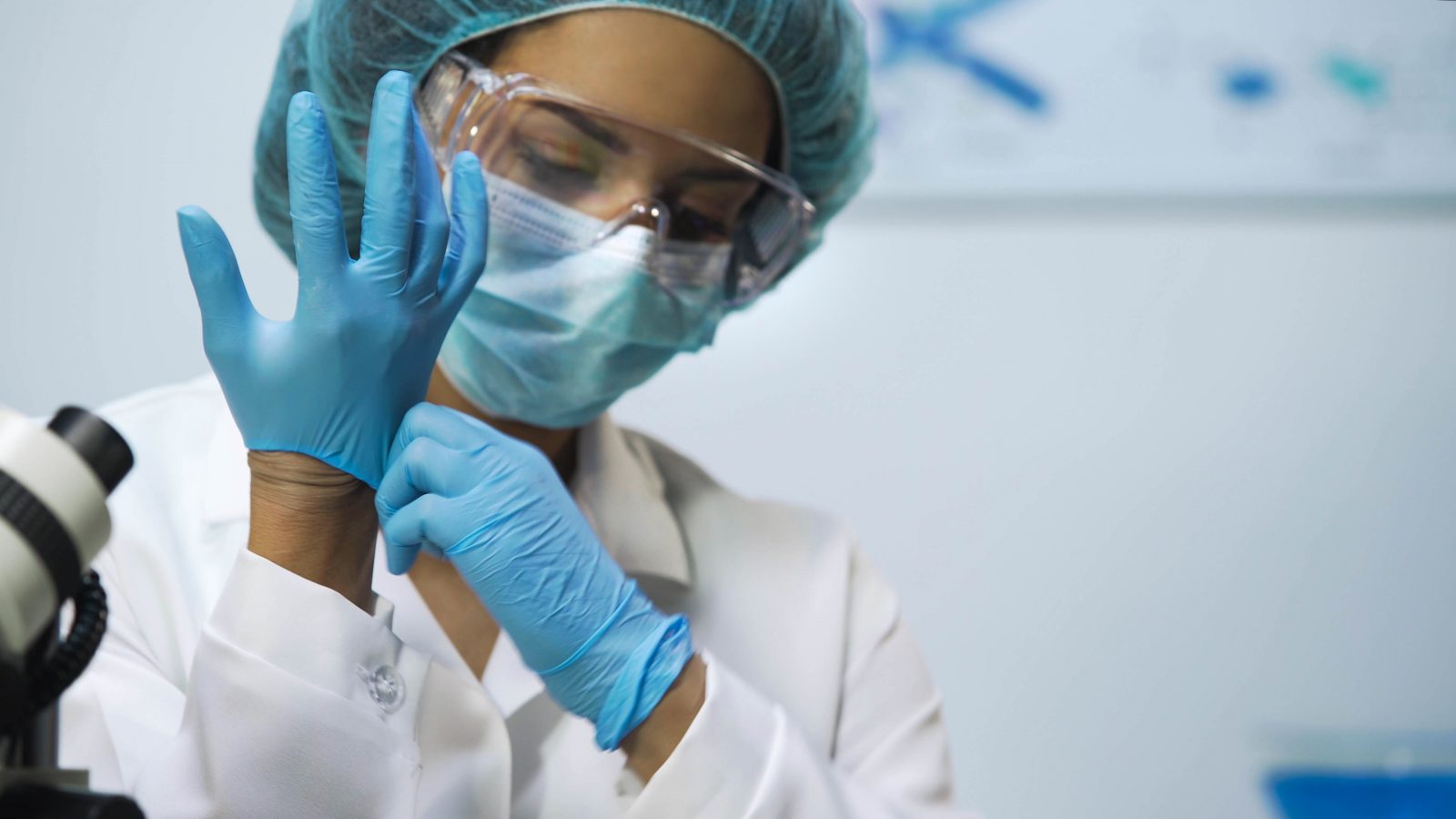 Biracial girl putting latex gloves on at laboratory, preparing for research