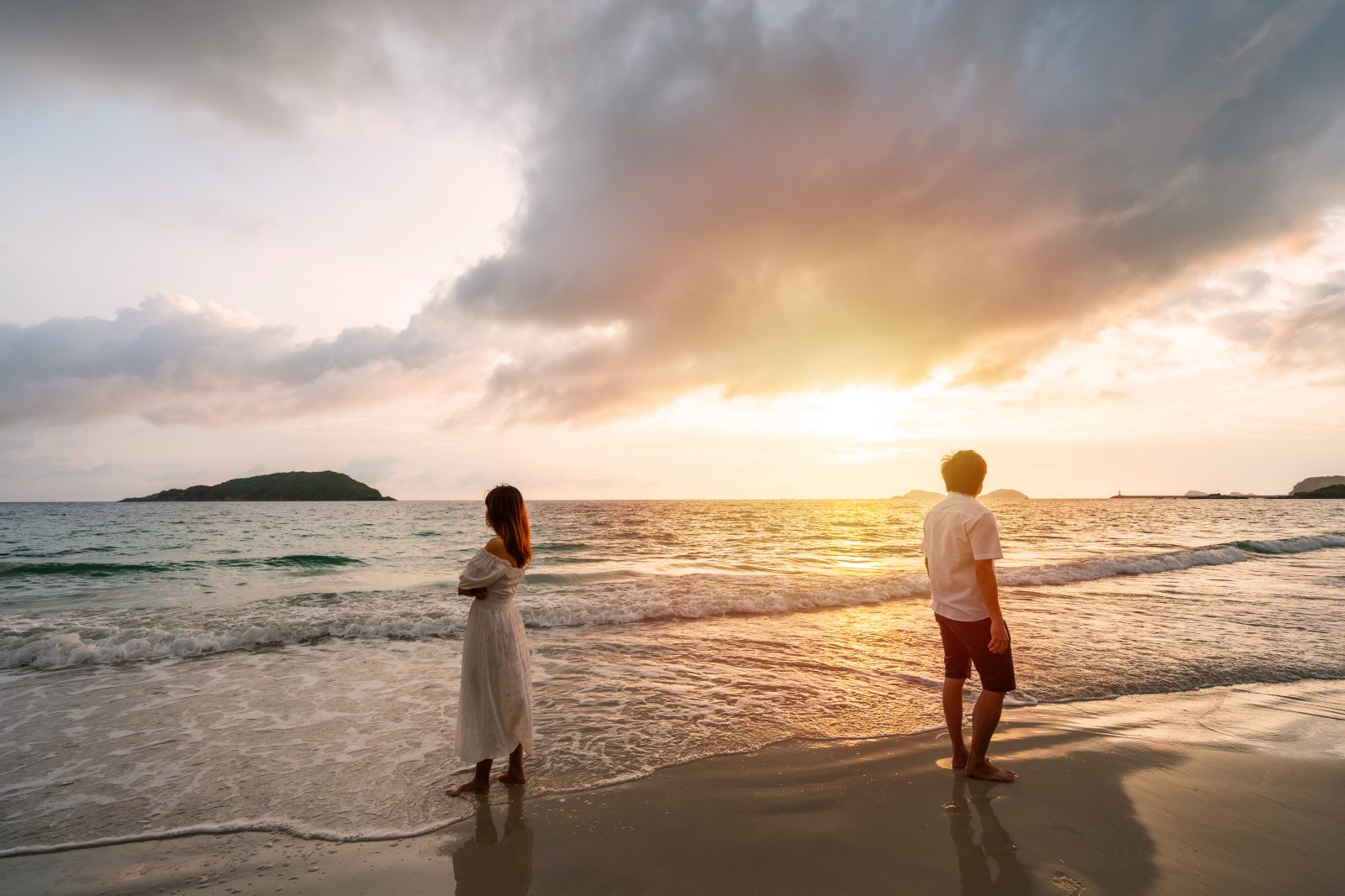 Couple standing on the beach at sunset are having problems with each other