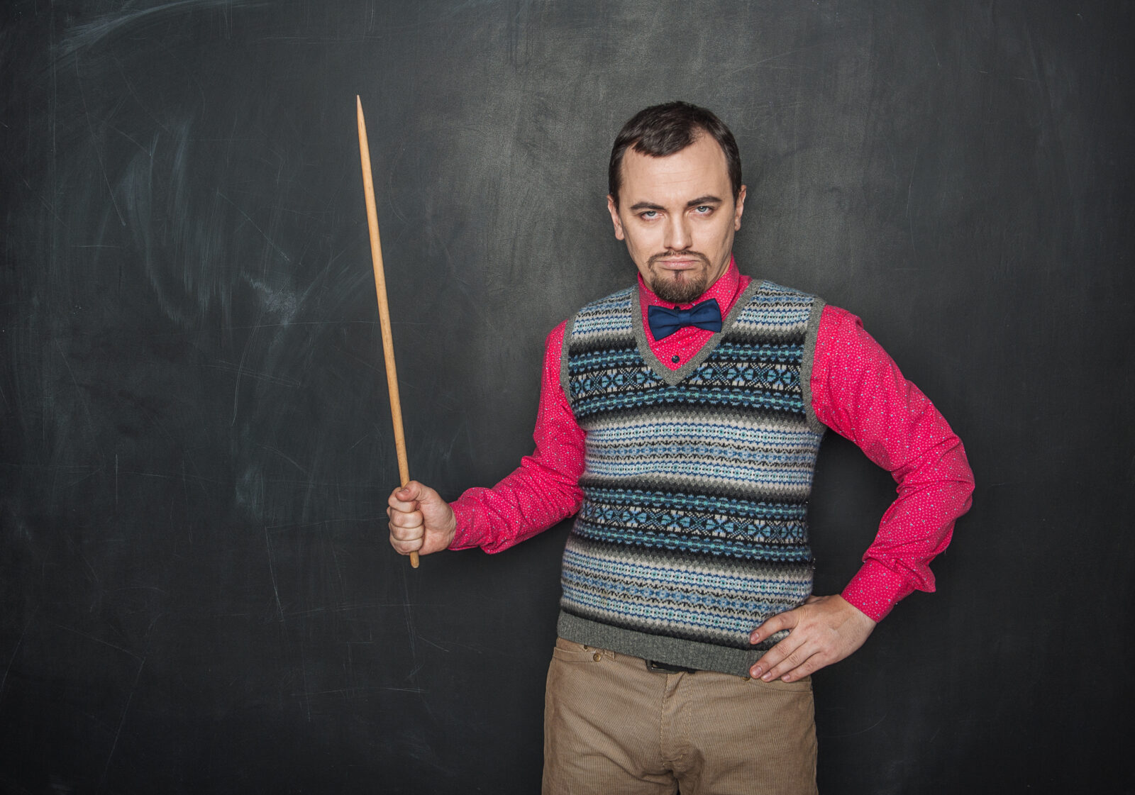 Angry teacher in retro style with pointer on blackboard