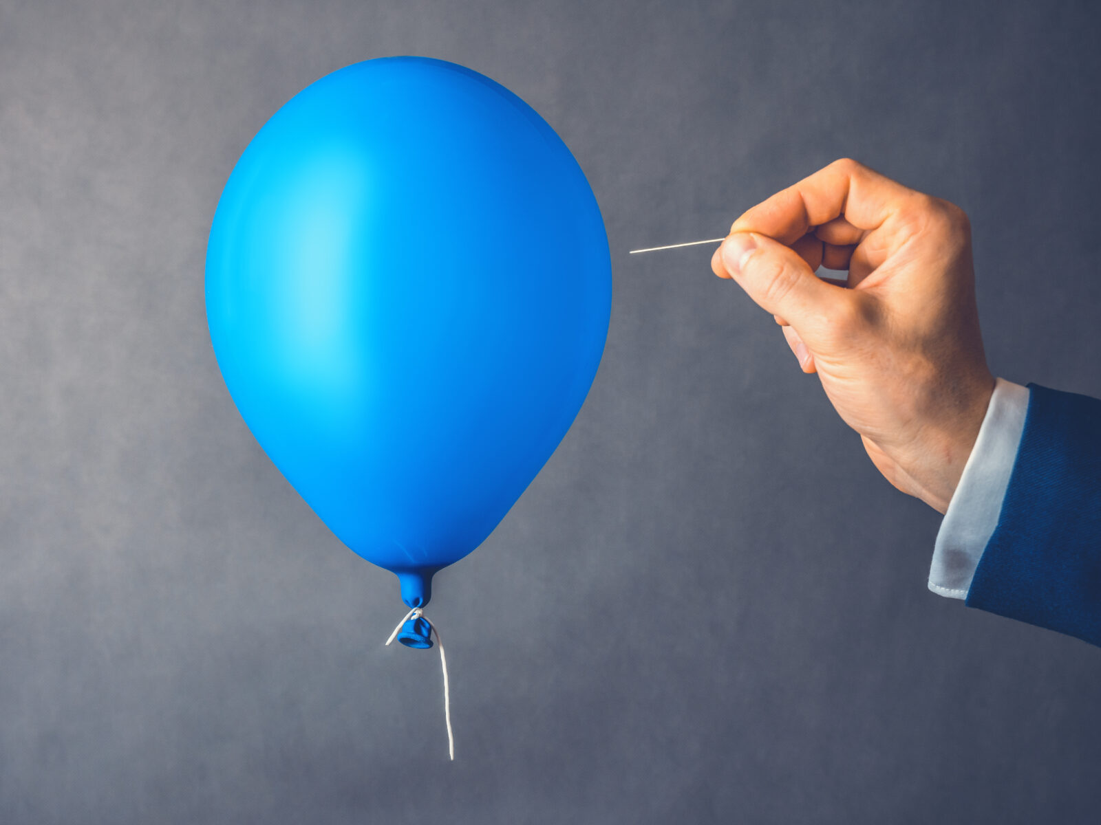 Blue balloon. Man hold needle directed to air balloon. Concept of risk. Copy space.
