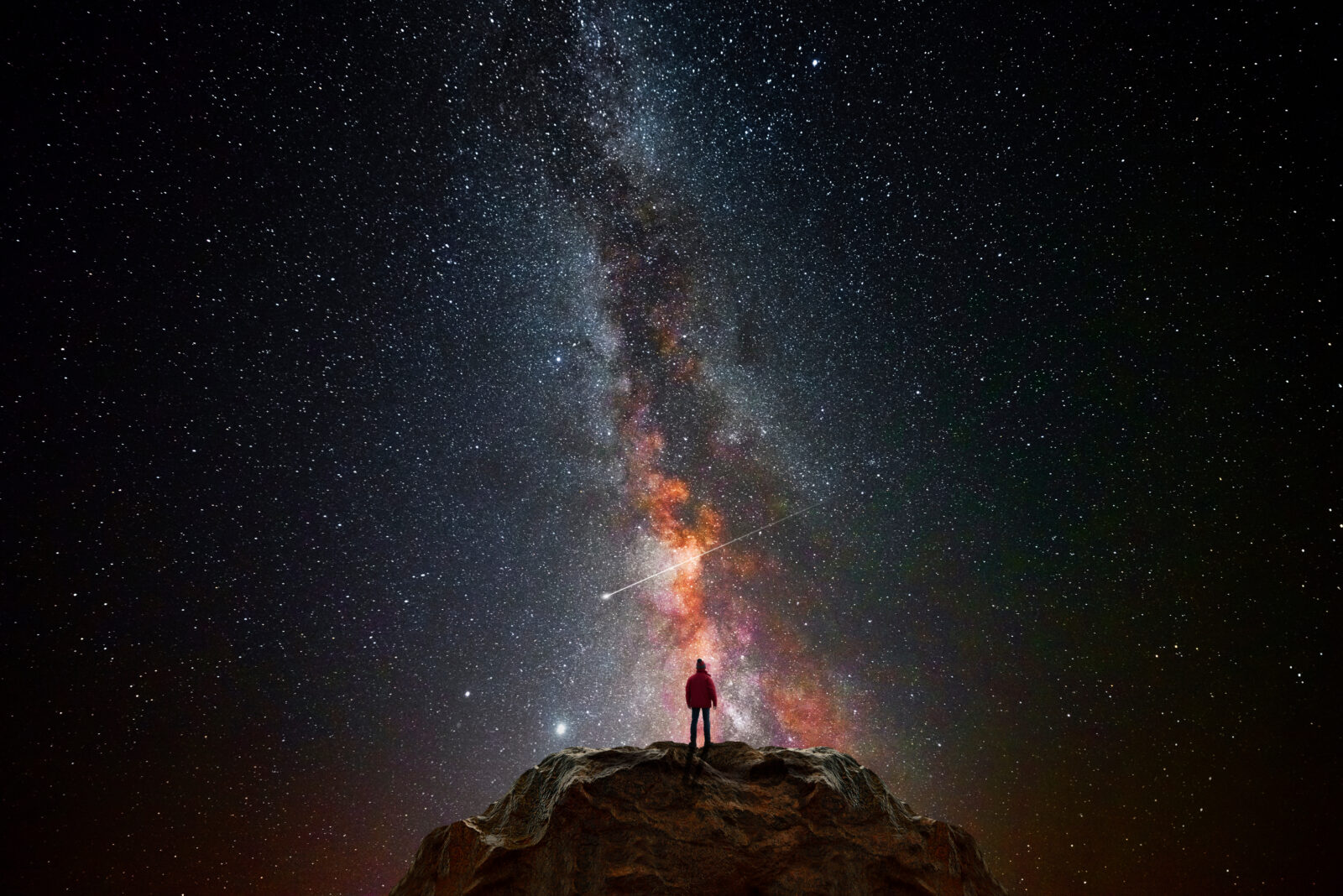 Man on top of a mountain observing the universe