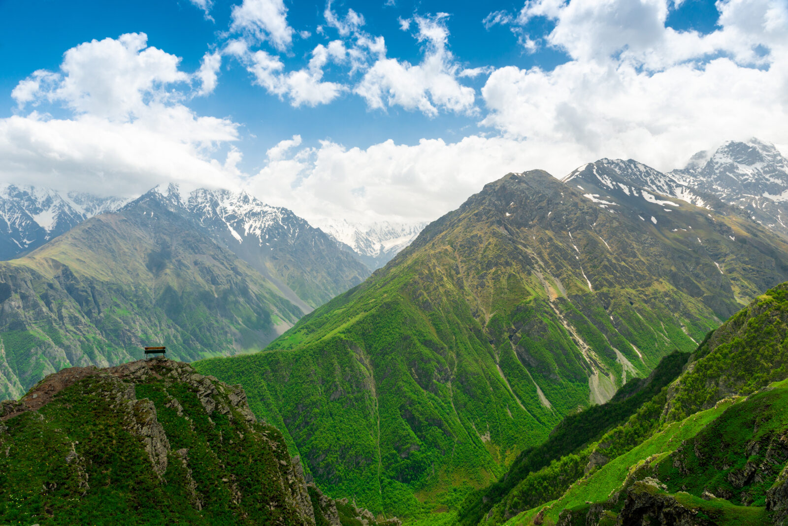 A lonely bench on an observation deck above a steep cliff with a picturesque view of the beautiful mountains