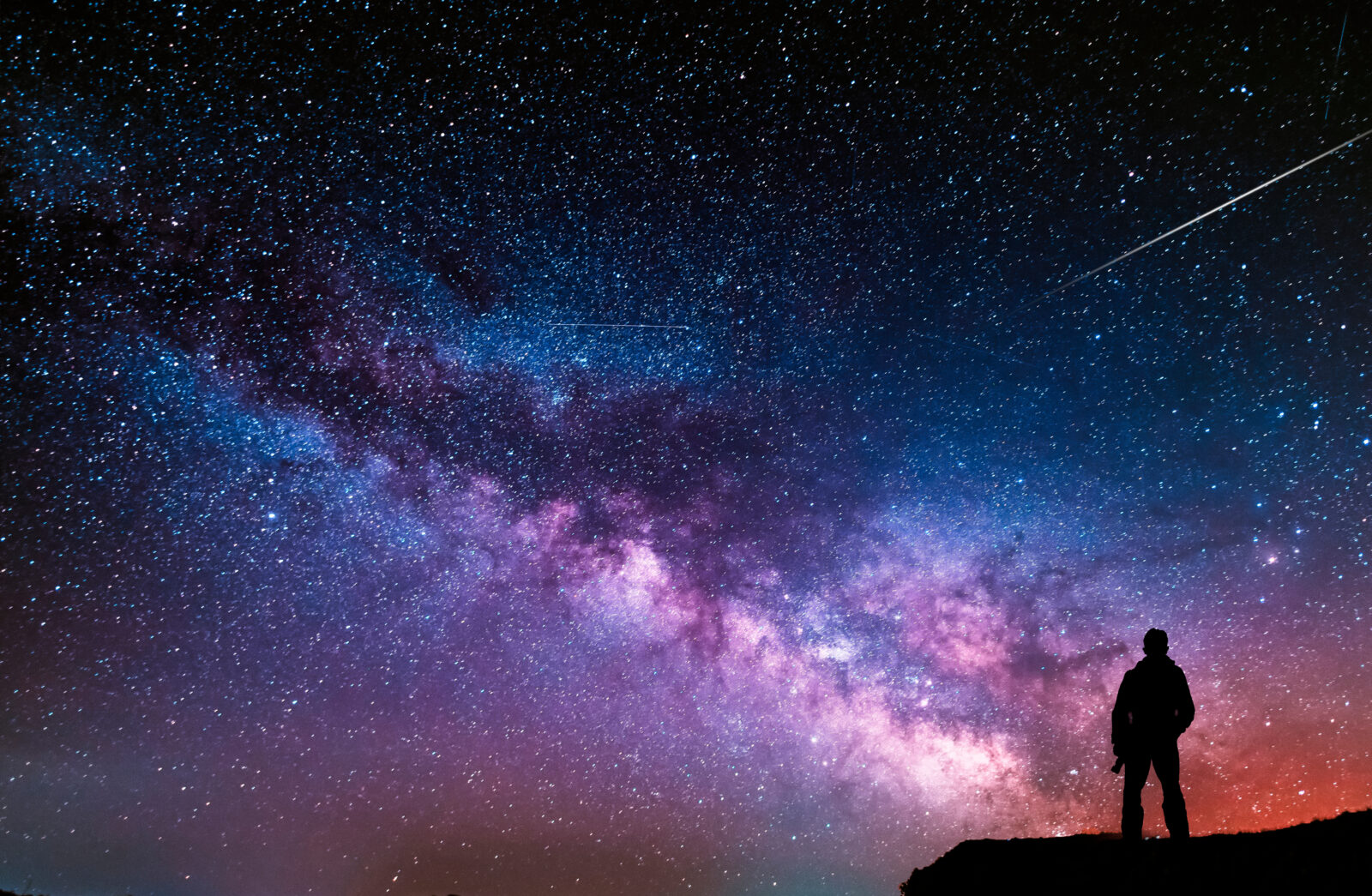 Beautiful starry night, man silhouette with a camera looking at the Milky Way galaxy.
